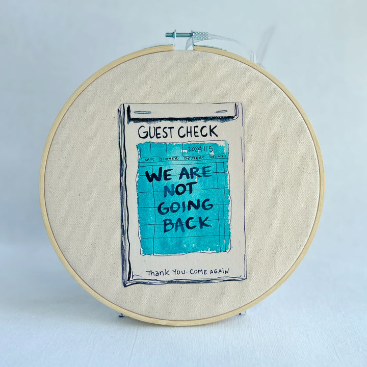 oatmeal linen canvas with a guest check design in deep blue-grey, with the words, we are not going back