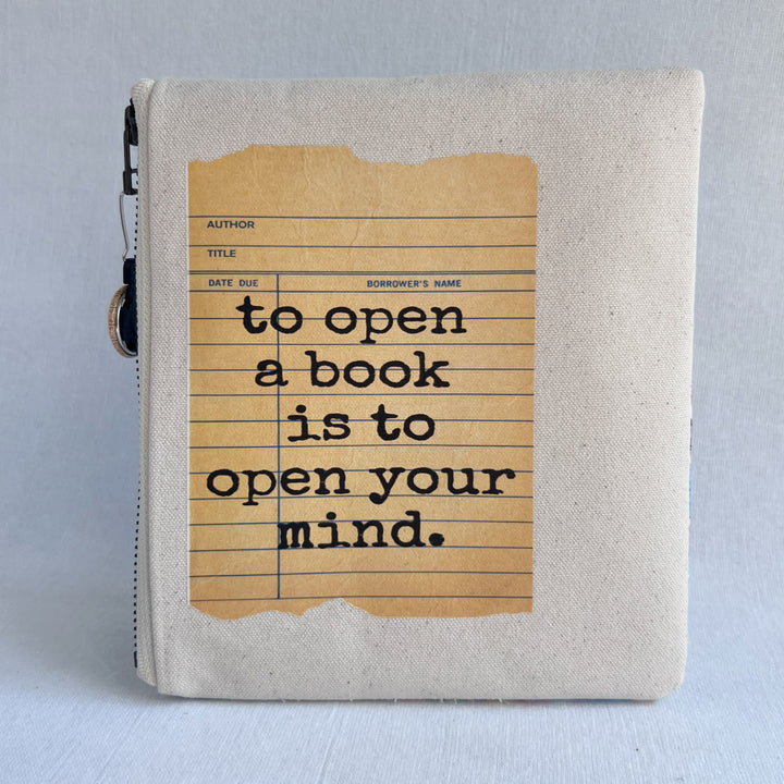 padded canvas zip bag with a yellow  library card and the words, To open a book is to open your mind, plus a colorful zipper pull and lining