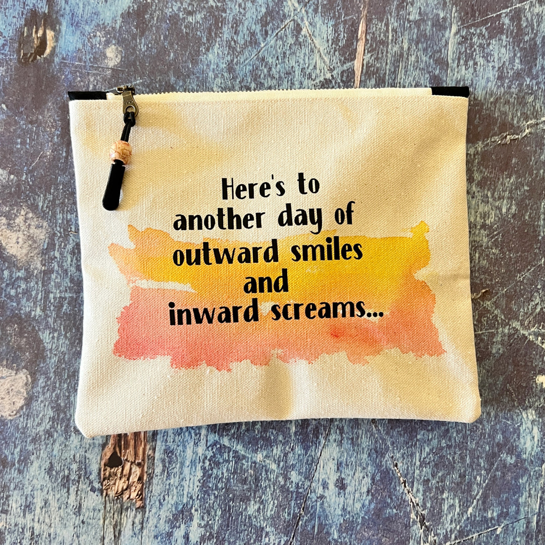 square canvas zip pouch with the words, Here's to another day of outward smiles and inward screams.'