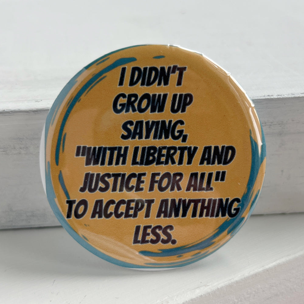 round pinback button with a yellow background with green streaks, and the words, "I didn't grow up saying, "with liberty and justice for all" to accept anything less."