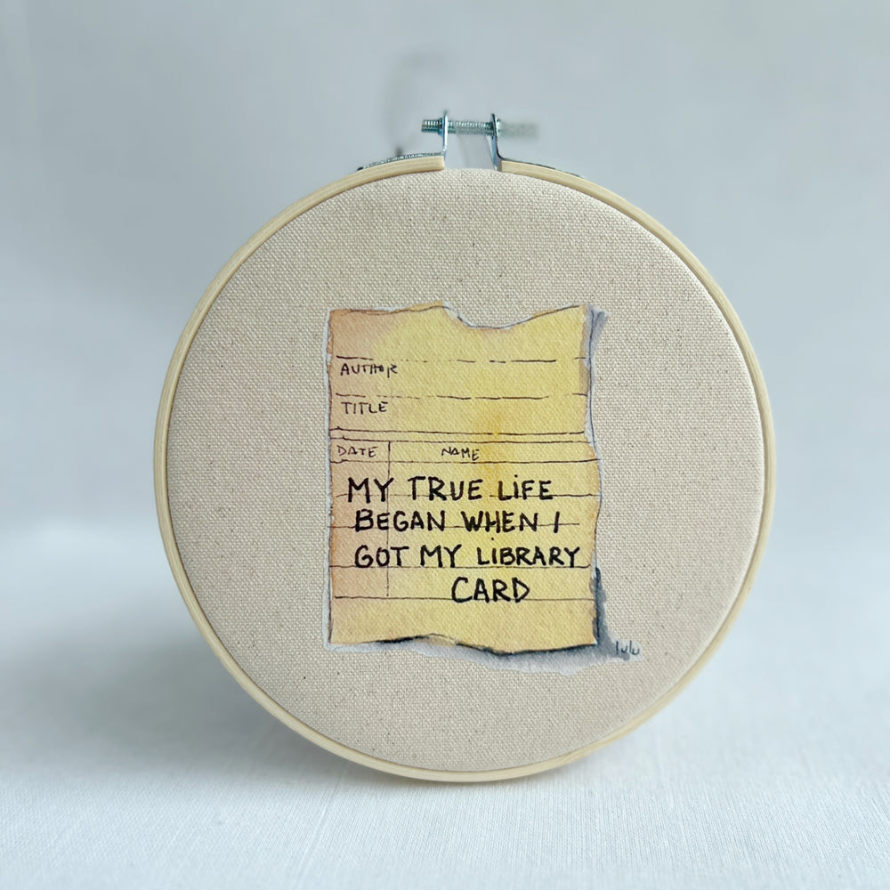 oatmeal colored canvas with a vinyl image of a watercolor library card, with the words, my true life began when i got my library card