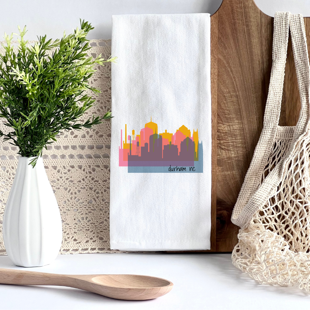 A white kitchen towel with a triple view of the downtown Durham NC skyline