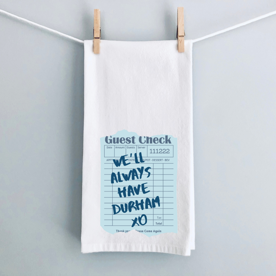 A white kitchen towel with a vintage guest check note in blue and the words, We'll always have Durham xo.