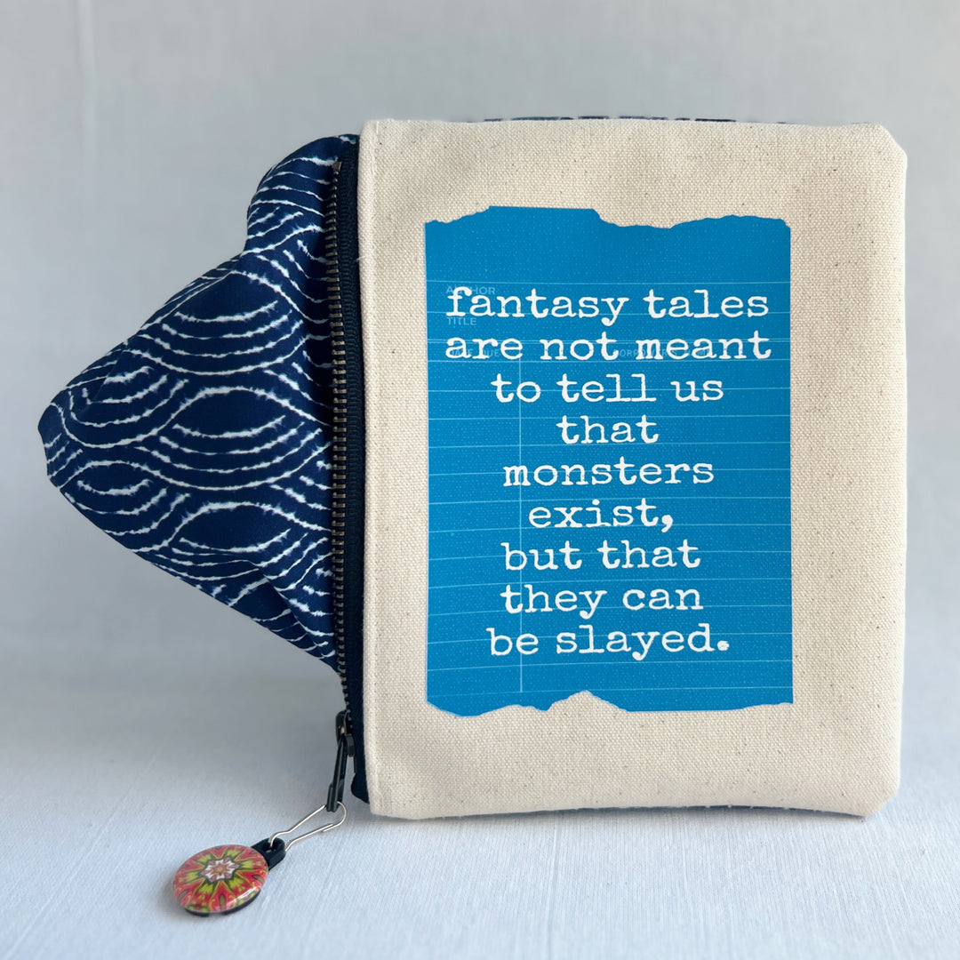 padded canvas zip bag with a yellow  library card and the words, Fantasy Tales are not meant to tell us that monsters exist, but that they can be slayed, plus a colorful zipper pull and lining