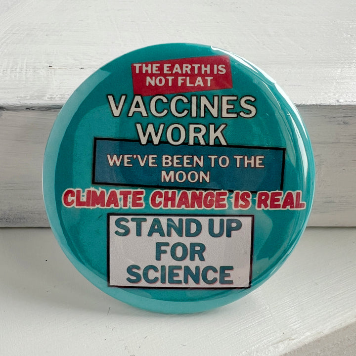 round, robin's egg blue pinback button on a white background with the words, "the earth is not flat. vaccines work. we've been to the moon. climate change is real. stand up for science."