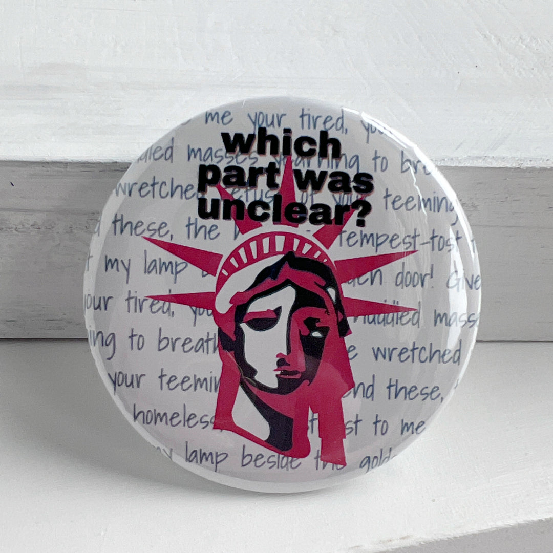 round pinback button with a white background, grey words spelling out some of the words on the base of Lady Liberty, such as give me your poor, your tired, your huddle masses. The words, "which part was unclear " label the top of the button, with a picture of Lady Liberty's head in red and blue.