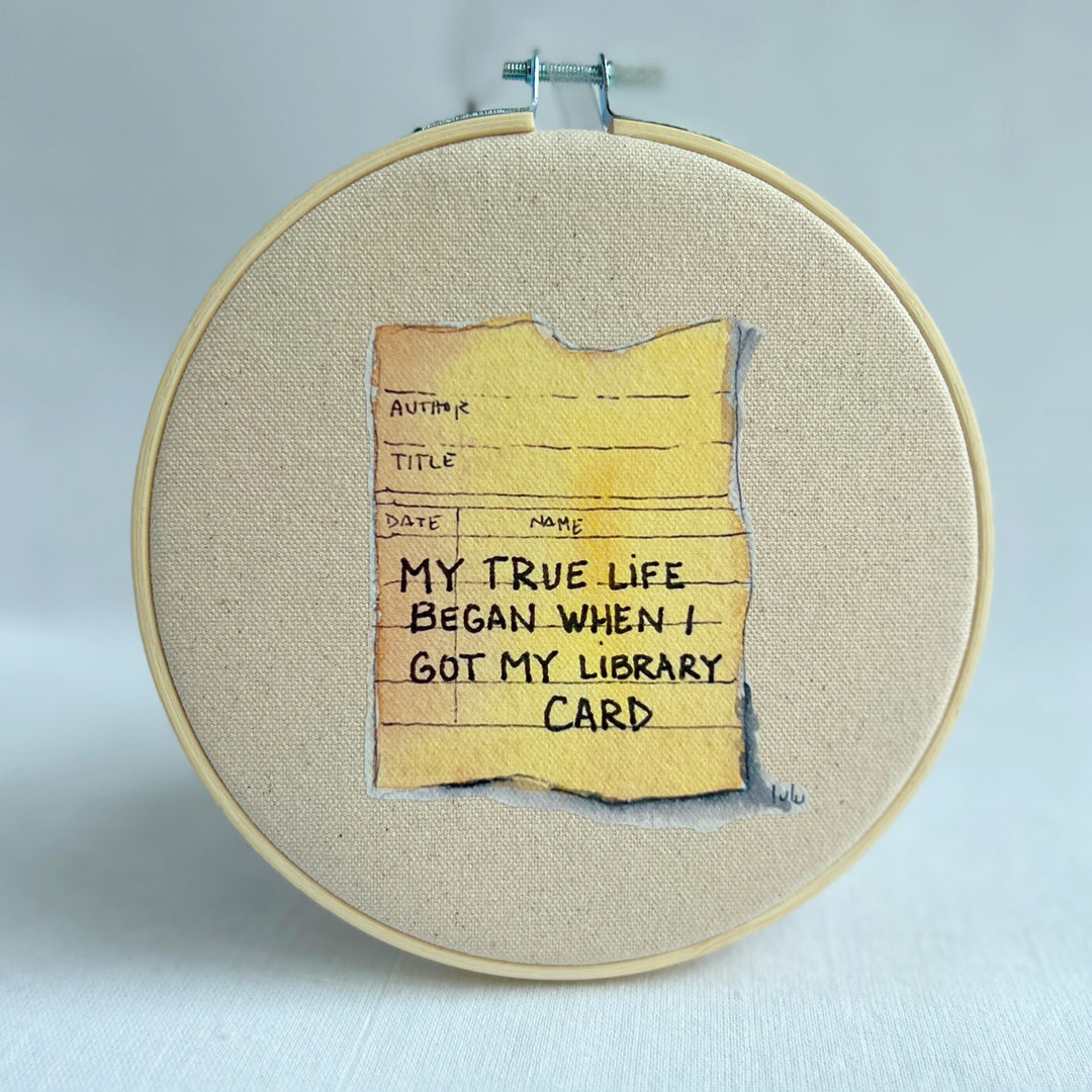 oatmeal colored canvas with a vinyl image of a watercolor library card, with the words, my true life began when i got my library card