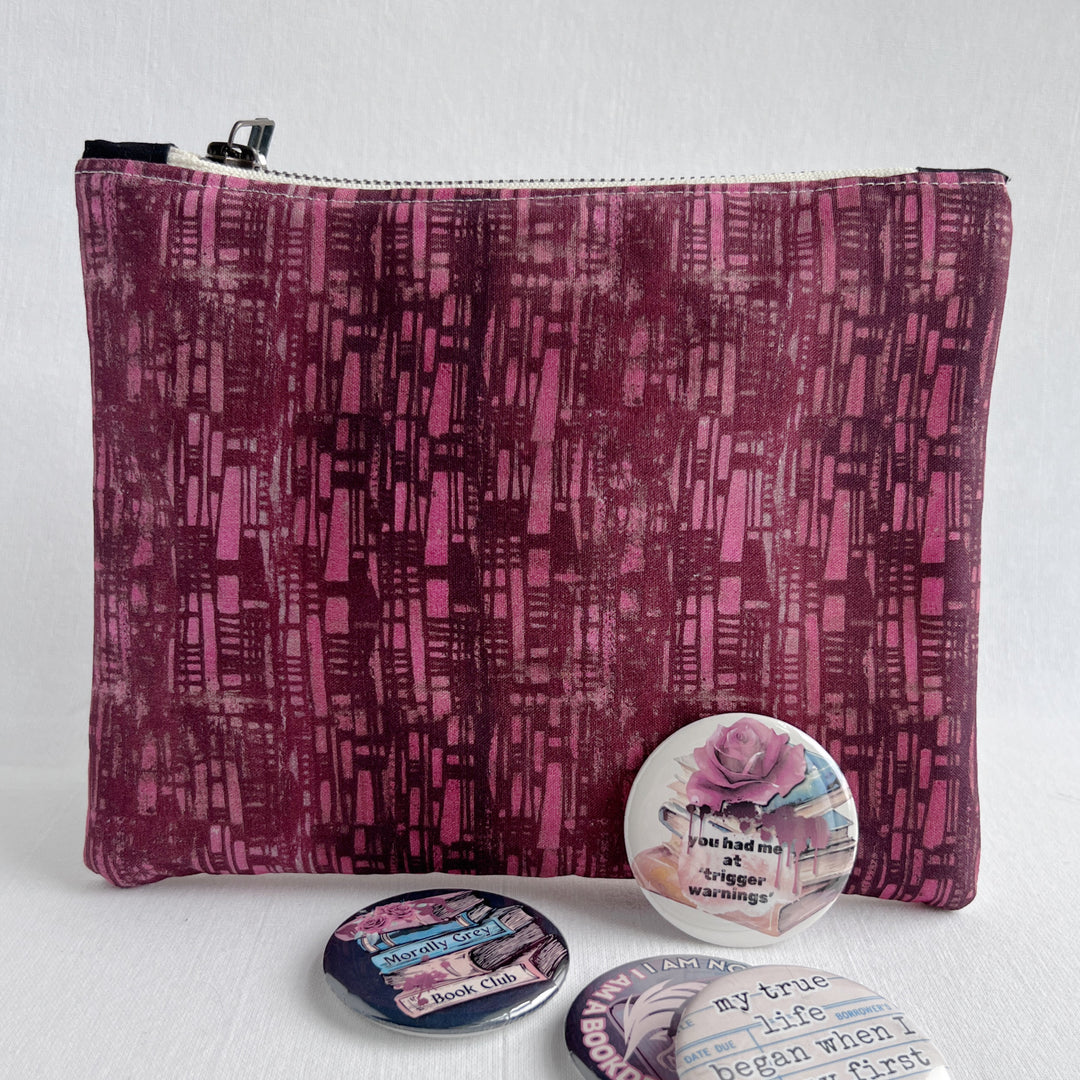 Tablet sleeve in pink and purple, with several pinback buttons scattered in front.