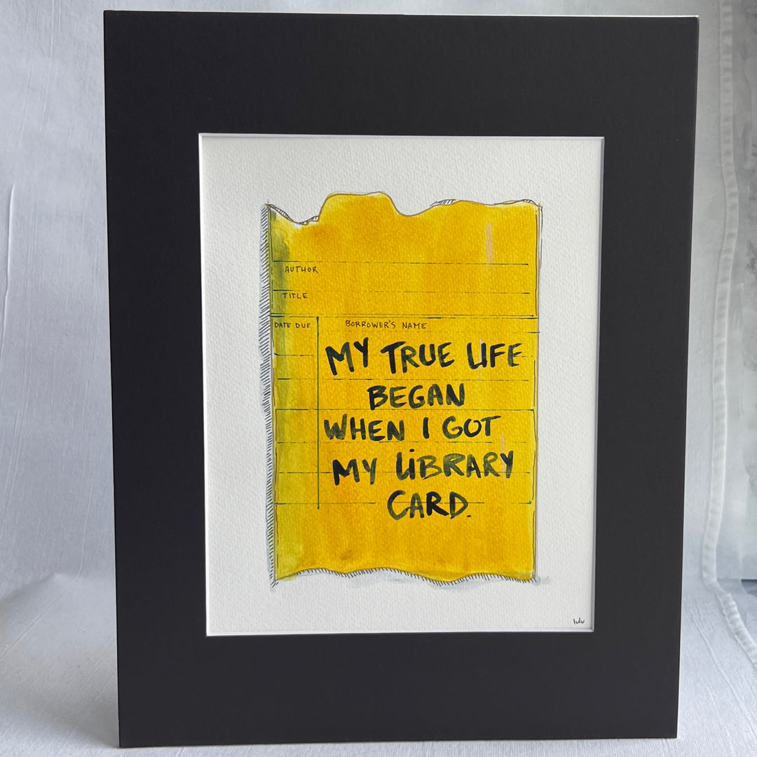 an original watercolor painting depicting a torn vintage library checkout card in shades of yellow with the words, my true life began when I got my library card, matted in black