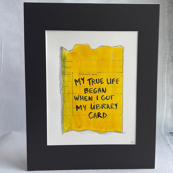 an original watercolor painting depicting a torn vintage library checkout card in shades of yellow with the words, my true life began when I got my library card, matted in black