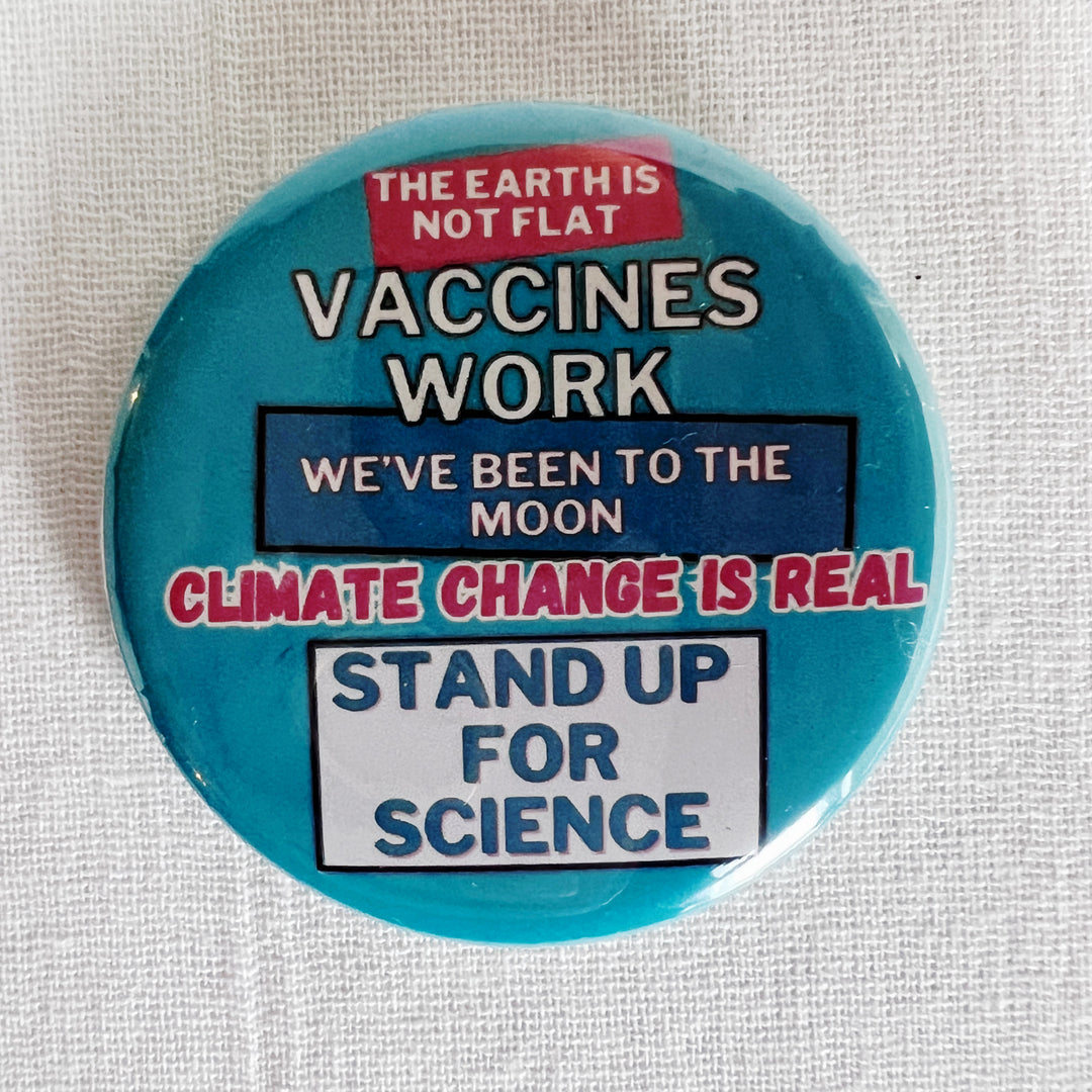 round, robin's egg blue pinback button on a white background with the words, "the earth is not flat. vaccines work. we've been to the moon. climate change is real. stand up for science."