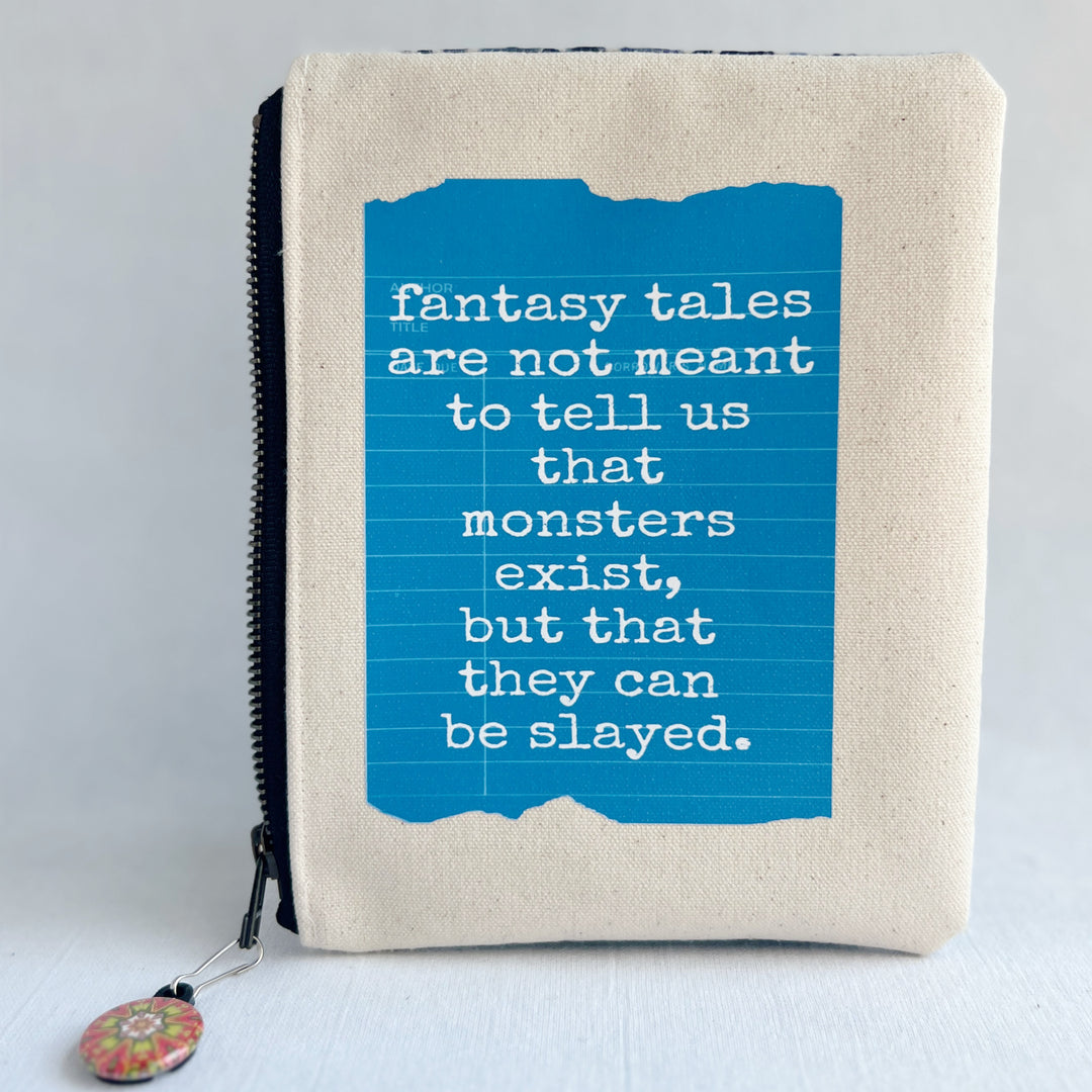 padded canvas zip bag with a yellow  library card and the words, Fantasy Tales are not meant to tell us that monsters exist, but that they can be slayed, plus a colorful zipper pull and lining