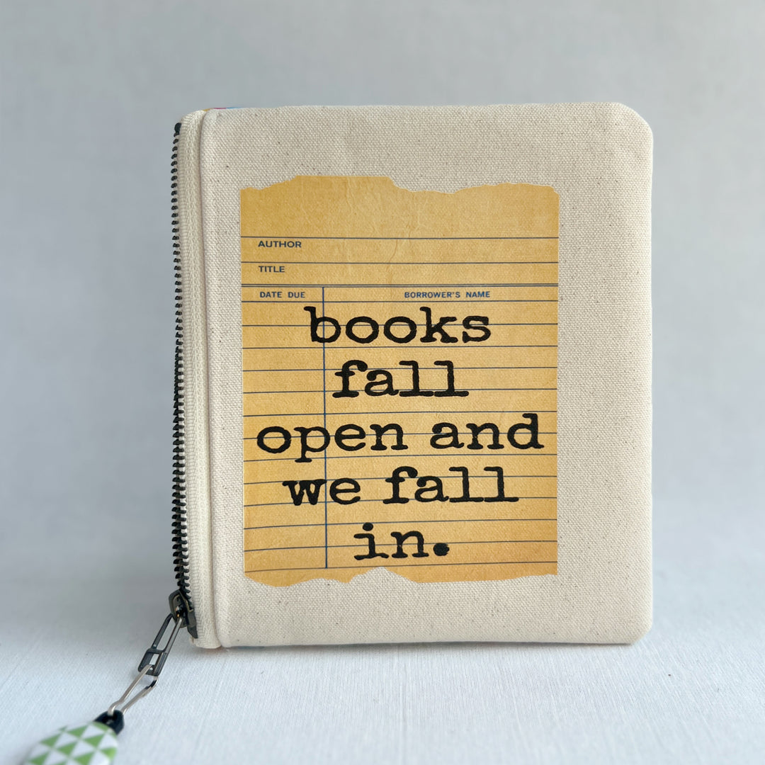 padded canvas zip bag with a yellow  library card and the words, Books fall open and we fall in, plus a colorful zipper pull and lining