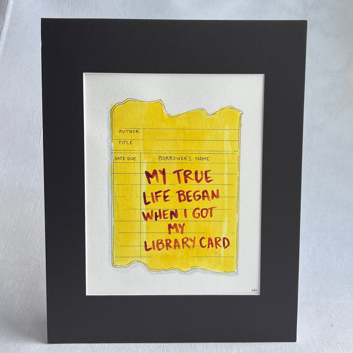 an original watercolor painting depicting a torn vintage library checkout card in shades of yellow with the words, my true life began when I got my library card, matted in black