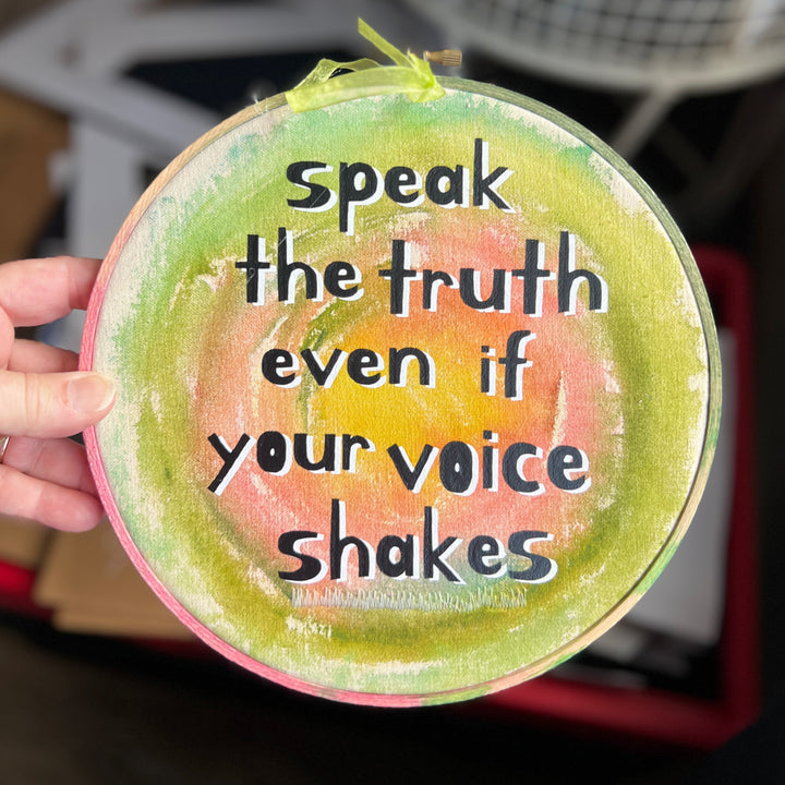 eight inch painted wooden embroidery hoop with canvas, painted with greens pinks and yellows, with the words, speak the truth, even if your voice shakes.