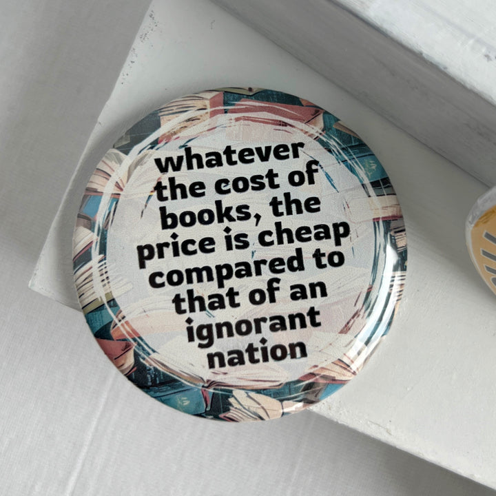 round pinback buttn with a background of colorful books, and the words, "whatever the cost of books, the price is cheeap compared to that of an ignorant nation."